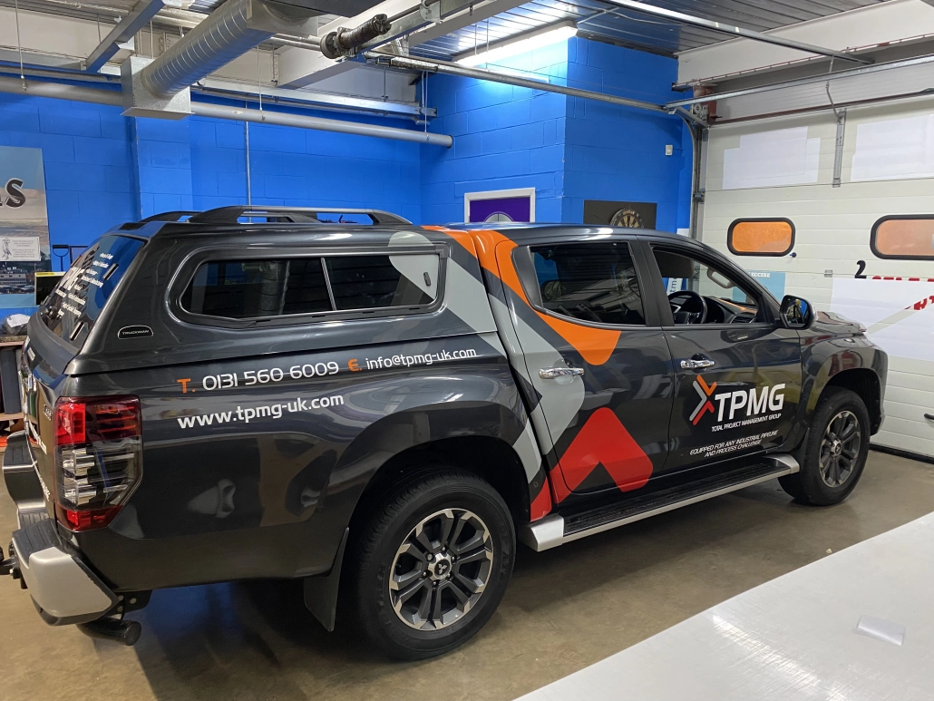 TPMG pickup with orange and white printed vinyl graphics fitted by Mac Signs
