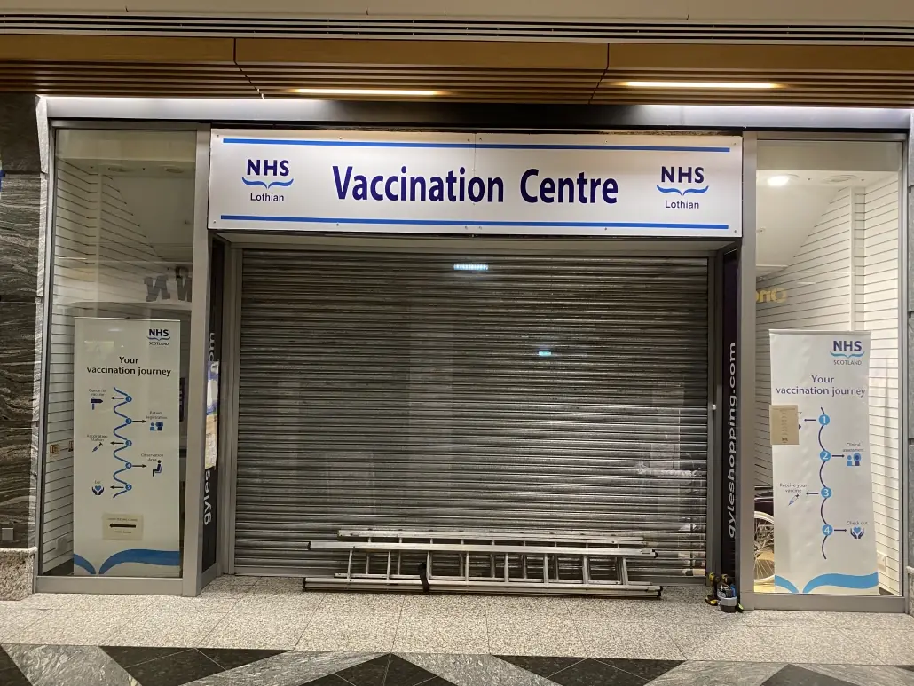 NHS Lothian Vaccination Centre entrance with printed header panel and window wayfinding graphics
