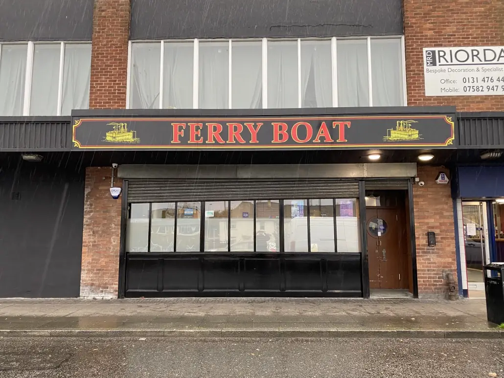 The Ferry Boat pub with an illuminated amber and black fascia sign above the frontage