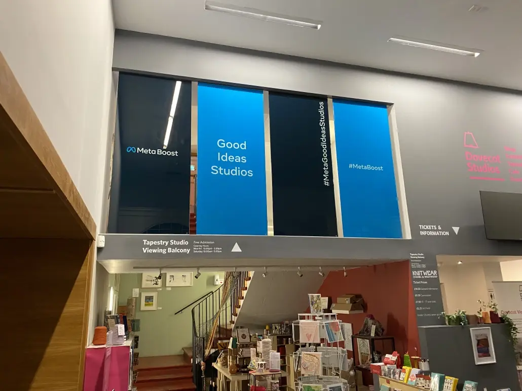 Dovecot Studios interior with printed blue window panels and wayfinding signage above the shop floor